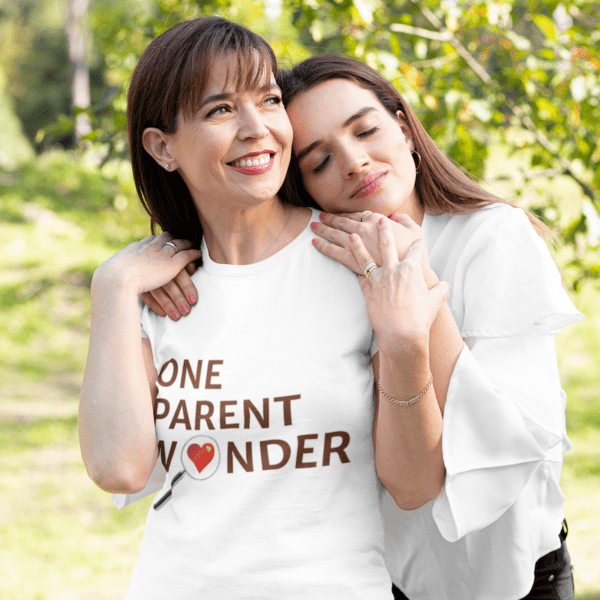 A mother in a "One Parent Wonder" shirt smiles with her daughter resting her head on her shoulder.