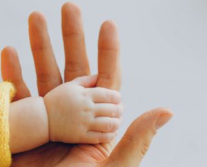 Close-up of a baby's hand holding an adult's fingers.