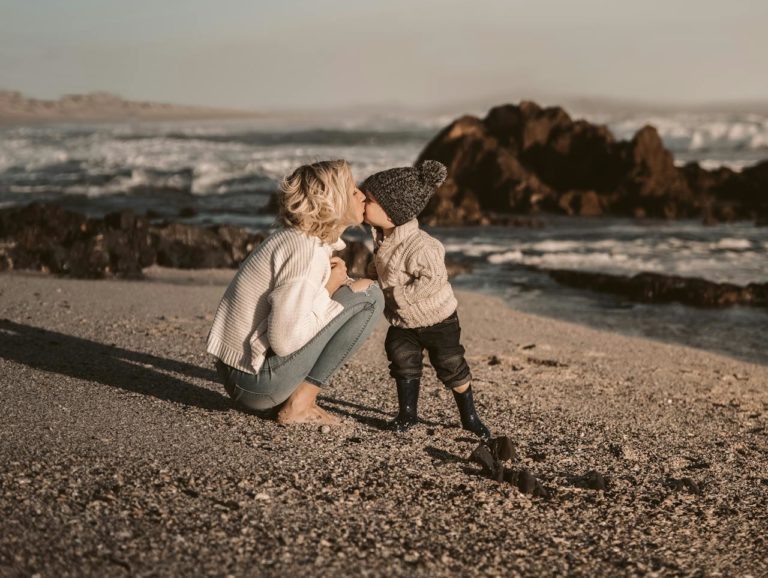 Mother and toddler kissing on a sunny beach.