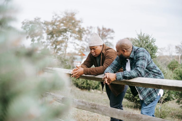 Father and son having a serious conversation by a fence.