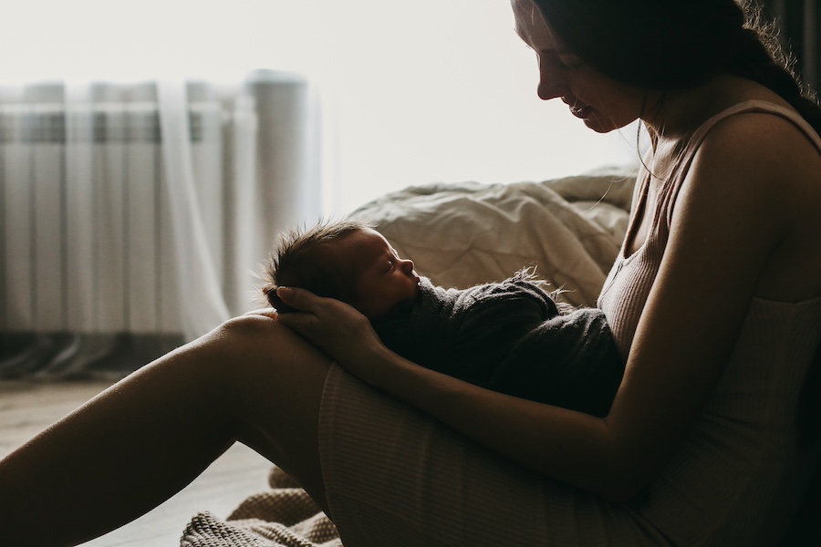 Tender moment between a mother and her newborn in a dimly lit room.