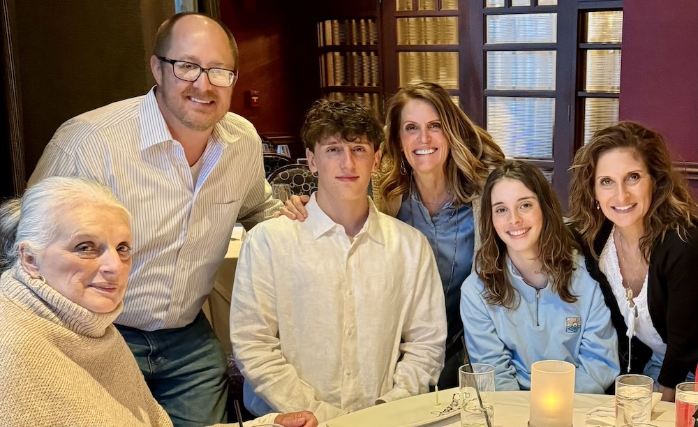 Elena Patrice with her family smiling at a dinner table.