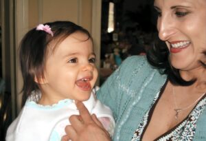 Mother smiling at baby daughter laughing in her arms, early parenting moment.