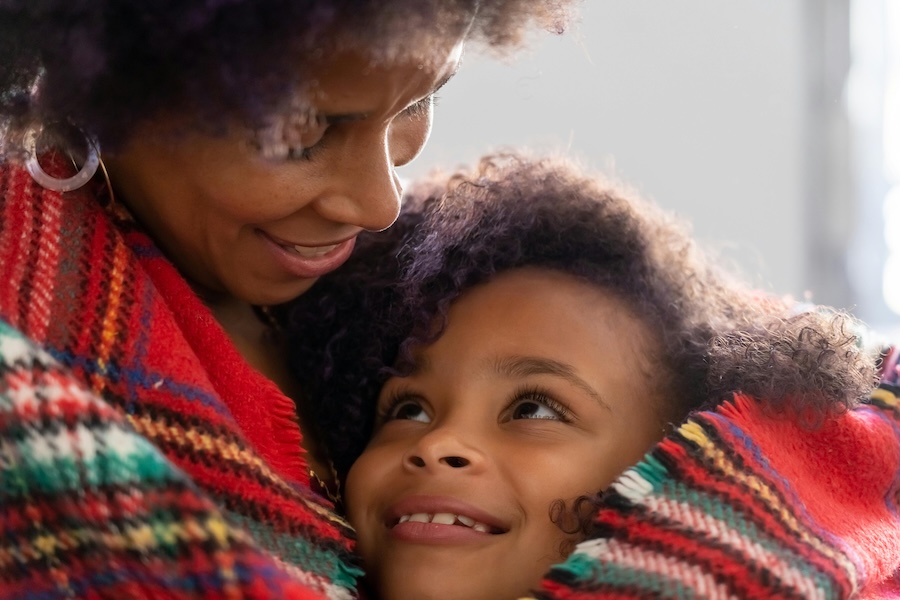 Mother wrapping her daughter in a warm blanket and smiling