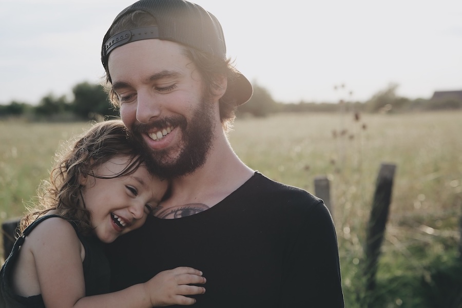 Loving father hugging his daughter outside in the sunshine