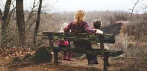 Single parent sitting on a bench with two children, showing love and resilience.