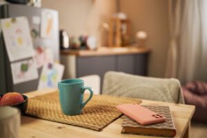 Kitchen table with notebook, coffee mug, phone, and child artwork for One Parent Wonder reflection guide